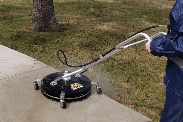 man cleaning concrete sidewalk with cleaning machine