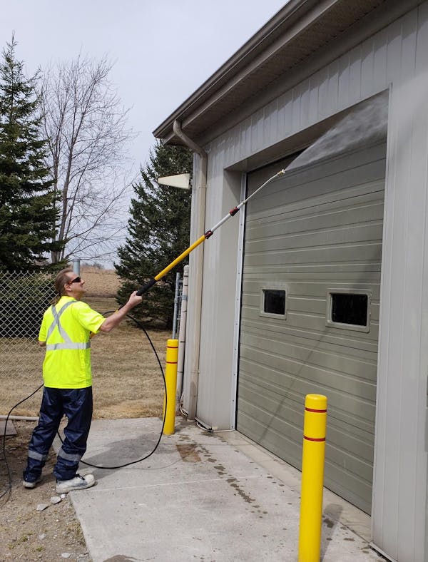 man with power washer spraying garage door