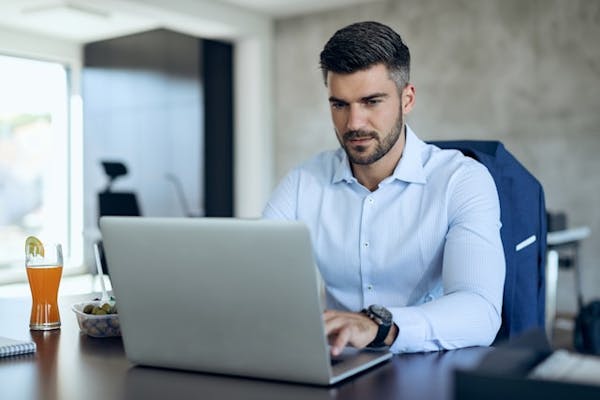 Focused businessman working on a laptop at his desk in a modern office.